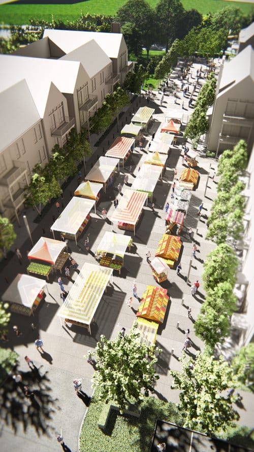 Aerial view of a street market with colorful tents lined up between buildings, surrounded by trees and people walking around.